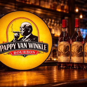 Puede incluir: Un letrero retroiluminado con las palabras "Pappy Van Winkle Bourbon" y una ilustración de un hombre fumando un cigarro. Tres botellas de bourbon con tapas rojas y doradas sobre una superficie de madera.