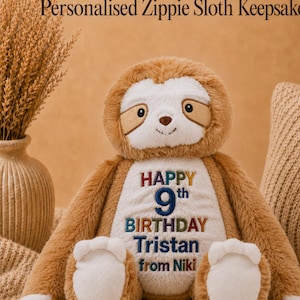 Könnte beinhalten: Ein Plüsch-Faultier mit braunem und weißem Fell, das auf dem Bauch den gestickten Text trägt: HAPPY 9th BIRTHDAY Tristan from Niki. Das Faultier hat ein weißes Gesicht, dunkelbraune Augenpartien und eine kleine braune Nase.