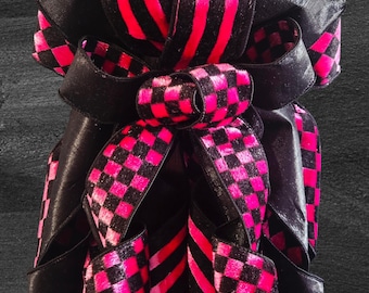 Lazo decorativo de terciopelo rosa fucsia y negro con estampado de cuadros/rayas.