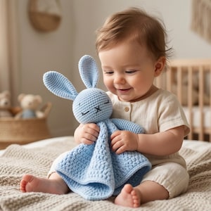 Pode incluir: Um coelhinho de crochê azul claro com orelhas compridas e um corpo tipo manta. O coelhinho tem olhos fechados e uma boca costurada. Um brinquedo macio projetado para bebês e crianças pequenas.