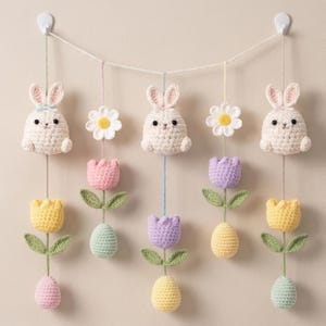 Può includere: Ghirlanda pasquale fatta a mano con coniglietti, margherite, tulipani e uova all'uncinetto. I coniglietti sono bianchi con orecchie rosa, i tulipani sono gialli, rosa e viola, e le uova sono in colori pastello.