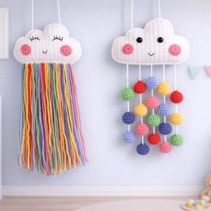 May include: Two handmade crochet cloud wall hangings. One cloud has rainbow yarn strands, the other has colorful crochet ball drops. Both clouds are white with pink cheeks, black eyes, and smiling faces. These nursery decorations add a whimsical touch.