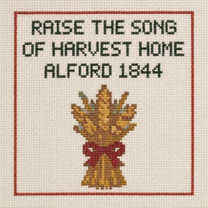 May include: A cross-stitch embroidery on off-white fabric featuring a red border. The text reads "RAISE THE SONG OF HARVEST HOME ALFORD 1844" in dark green. Below the text is a golden-yellow wheat sheaf tied with a red bow, stitched in detail.