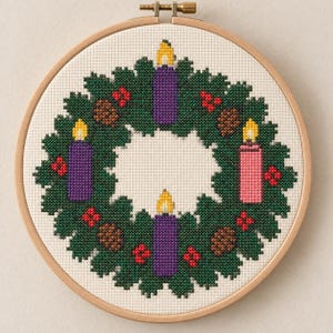 May include: A circular wooden embroidery hoop containing a cross-stitch pattern of an Advent wreath. The wreath features dark green holly leaves, brown pinecones, red berries, and four candles with yellow flames: three purple and one pink.