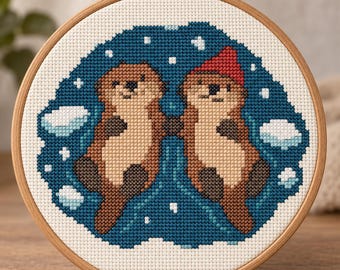 Peut inclure: Un tambour à broder circulaire en bois contenant un motif au point de croix représentant deux loutres brunes flottant dans une eau bleu foncé. L'une des loutres porte un bonnet rouge. Le motif inclut des plaques de glace et de la neige.