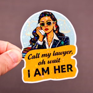 May include: A sticker featuring a pop art style illustration of a woman wearing sunglasses and a suit, holding a phone. The sticker has the text "Call my lawyer, oh wait I AM HER" in a yellow banner.