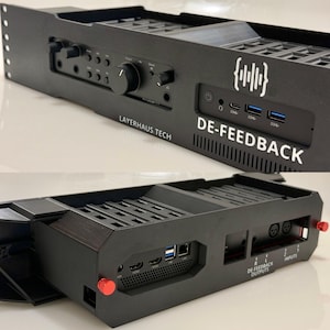 May include: Black electronic device with the text "DE-FEEDBACK" and "LAYERHAUS TECH". It features multiple ports, dials, and a logo. The device has a structured design with a series of slots and openings.