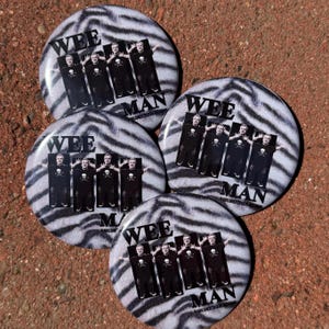 May include: Four circular pin-back buttons featuring a black and white zebra stripe background. Each button displays four identical photographic images of a person wearing a black t-shirt with a skull graphic, with the text WEE MAN printed.