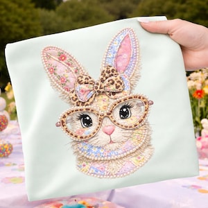 Peut inclure: Un tissu carré vert clair avec un visage de lapin fantaisiste avec des lunettes et un nœud. Le lapin a des oreilles en patchwork et un nœud avec un motif léopard. Le lapin porte des lunettes rondes.