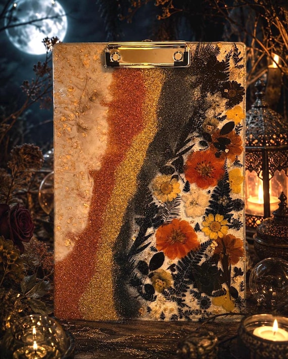Deep midnight-toned resin clipboard embedded with real botanicals — a desk tool that doubles as a piece of moody floral art.