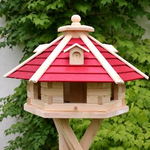 May include: A wooden birdhouse with a red roof and natural wood accents. The birdhouse has a small, decorative birdhouse on the front and is supported by a wooden stand. The birdhouse is designed to attract birds and add a decorative touch to any garden.