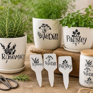 May include: A collection of ceramic herb pots and plant markers. The pots are labeled "Rosemary", "Dill", and "Parsley" with matching plant markers. A small jar with a wooden lid and a pair of scissors are also present.
