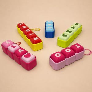 May include: A collection of colorful, modular letter blocks in various arrangements. The blocks are in shades of red, yellow, pink, blue, and green, spelling out words and letters. Each block has a different letter or symbol on it.