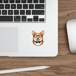 Könnte beinhalten: Ein Aufkleber mit einem Cartoon-Corgi, der eine Brille und eine blaue Fliege trägt. Der Corgi hat orange-weißes Fell und lächelt. Der Aufkleber befindet sich auf einer weißen Oberfläche neben einer Laptop-Tastatur.