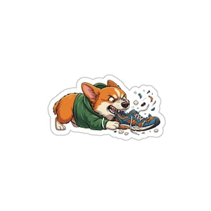 May include: A sticker depicting a cartoon corgi in a green hoodie, biting a blue and orange trainer. The corgi has an angry expression, with pieces of the trainer scattered around. The sticker has a white border.