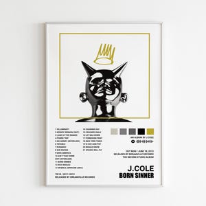 Könnte beinhalten: Gerahmtes Poster mit einer schwarzen und silbernen gehörnten Kopfskulptur und Krone auf weißem Hintergrund. Das Poster enthält eine Titelliste, den Albumtitel "BORN SINNER" und den Künstlernamen "J. Cole".