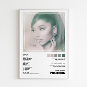 May include: A framed poster featuring Ariana Grande. The image is a portrait of the singer with a teal tint. The poster includes the album title "POSITIONS", tracklist, and release information. The color palette includes shades of teal, gray, and beige.