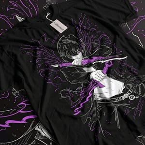 Puede incluir: Camiseta negra con una ilustración de un personaje sosteniendo una espada morada. El diseño incluye detalles morados y una etiqueta con "silkensoul". El estilo es similar al arte anime o manga.