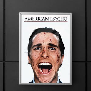 Könnte beinhalten: Gerahmtes Filmplakat für "American Psycho" mit einem Nahaufnahme-Porträt eines Mannes mit blutverschmiertem Gesicht, offenem Mund und geweiteten Augen. Der Titel steht in roter Schrift.