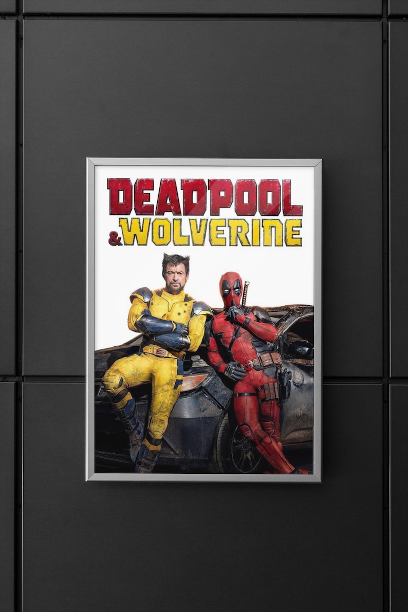 Puede incluir: Un p&oacute;ster enmarcado con el texto "DEADPOOL & WOLVERINE" en rojo y amarillo. La imagen muestra dos personajes disfrazados, uno de amarillo y negro, el otro de rojo, apoyados en un coche.