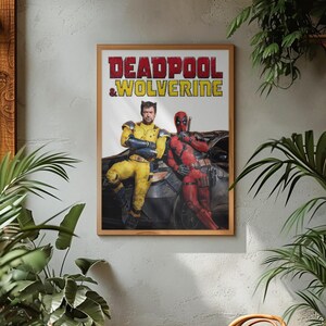 Puede incluir: Un p&oacute;ster enmarcado con el texto "DEADPOOL & WOLVERINE" en rojo y amarillo. La imagen muestra dos personajes disfrazados, uno de amarillo y otro de rojo, apoyados en un coche. El p&oacute;ster est&aacute; en un marco de madera, sobre una pared gris.
