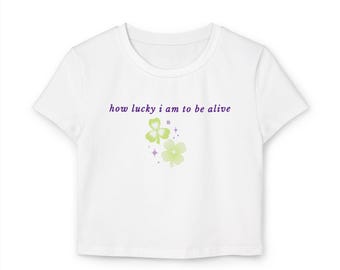 how lucky i am to be alive Baby Tee | clover floral graphic, purple text