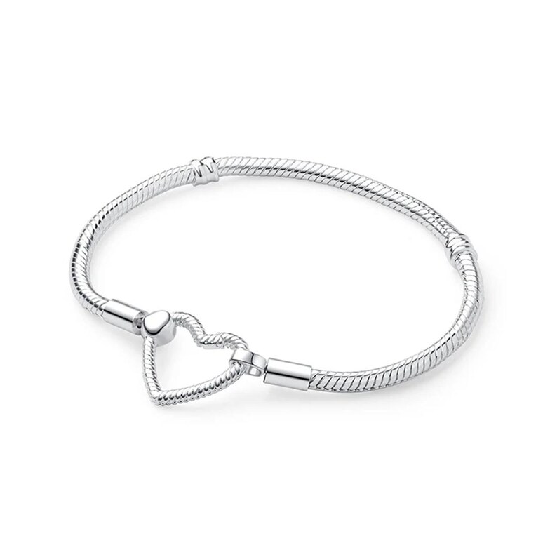 May include: A silver-toned snake chain bracelet featuring a heart-shaped clasp. The bracelet has a flexible, textured link design with two fixed stations along the band and a polished heart-shaped closure that connects the two ends of the chain.