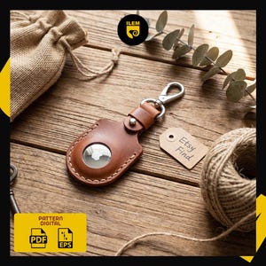 May include: A brown leather AirTag holder with a silver clasp and a stitched border. The holder is on a wooden surface with a tag that says "Etsy Find". A PDF and EPS digital pattern is also visible.