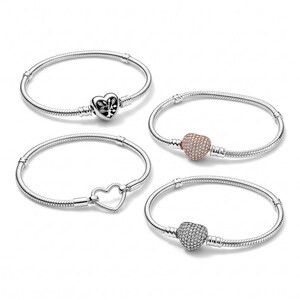 May include: Four silver-tone snake chain bracelets arranged in a group. One features a heart-shaped charm with a tree design, one has a rose gold-tone pav&eacute; heart charm, one has a silver-tone pav&eacute; heart charm, and one has an open heart clasp.