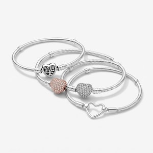 May include: Four silver-tone snake chain bracelets. One features a heart-shaped charm with a tree design, one has a rose gold-tone pav&eacute; heart charm, one has a silver-tone pav&eacute; heart charm, and one has a simple open heart-shaped clasp.