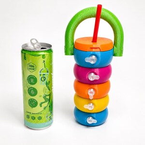 May include: A tall, slim green aluminum beverage can with a 200mg caffeine label next to a stackable, multi-colored plastic container set. The container features a bright green arched handle, an orange lid with a red straw, and four colorful segments.