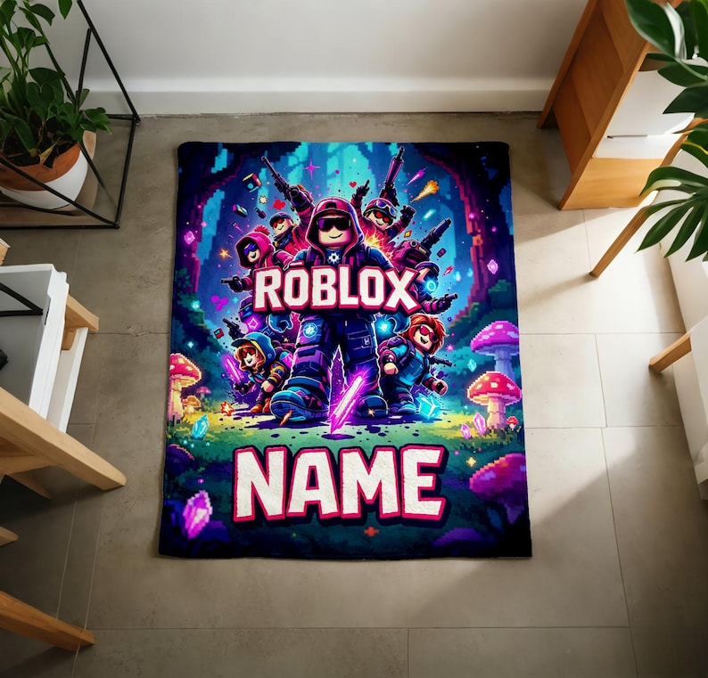 Puede incluir: Una manta rectangular con un dise&ntilde;o vibrante con tem&aacute;tica de Roblox. La manta muestra un grupo de personajes de Roblox con la palabra "ROBLOX" en un lugar destacado. Debajo, la palabra "NAME" est&aacute; escrita en letras grandes, lo que sugiere personalizaci&oacute;n.