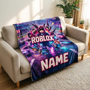 May include: A plush blanket featuring a vibrant design with the word "ROBLOX" and the word "NAME" in large, bold letters. The blanket showcases a colorful illustration of characters and race cars in a dynamic, action-packed scene.