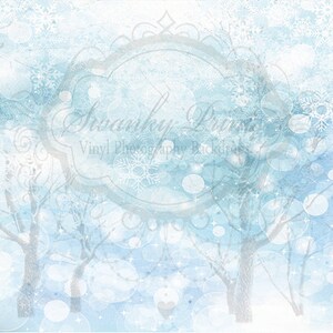 May include: A digital background image with a watercolor effect. The background is a light blue color with white snowflakes and white circles. There are also two trees in the background, which are also white. The text "Swanky Prints Vinyl Photography Backdrops" is in the center of the image.