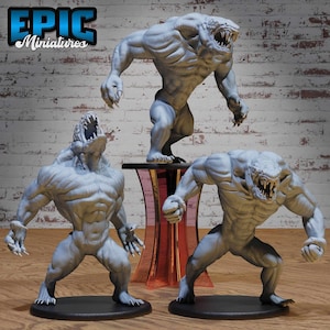 Puede incluir: Tres figuras de monstruos grises en poses dinámicas. Las figuras tienen dientes y garras afiladas, con cuerpos musculosos. Una está sobre una pequeña mesa. La esquina superior izquierda de la imagen tiene el texto "EPIC Miniatures".