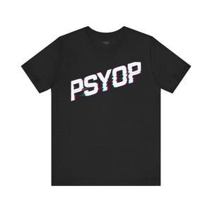 May include: Black crew neck t-shirt with the word "PSYOP" in white, with a red and blue glitch effect. The text is angled across the front of the shirt. The shirt is made of a soft material.