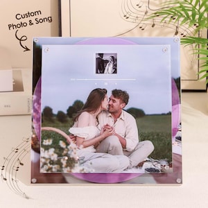 May include: A personalized photo and song print featuring a couple kissing. The print is mounted on a clear acrylic panel with a purple vinyl record design. The text "Custom Photo & Song" is visible.