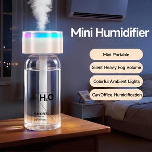 Op de afbeelding: Een heldere glazen mini-luchtbevochtiger met een witte bovenkant en kleurrijke omgevingslichten. De luchtbevochtiger heeft de tekst "H2O" en "HUMIDIFIER" op de voorkant. De afbeelding bevat ook de tekst "Mini Humidifier", "Mini Portable", "Silent Heavy Fog Volume", "Colorful Ambient Lights" en "Car/Office Humidification".