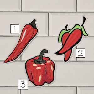 May include: Three embroidered patches of red peppers. Patch 1 is a long, slender chili pepper with a black stem. Patch 2 is a curved pepper with a green stem and top. Patch 3 is a bell pepper with a green stem.