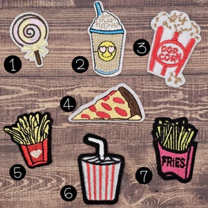 Könnte beinhalten: Sieben gestickte Aufnäher mit Speisen und Getränken: ein Lutscher, ein Kaffeegetränk mit Smiley-Gesicht, ein Popcorn-Eimer, ein Pizzastück, zwei Portionen Pommes frites und ein gestreifter Becher mit Strohhalm, jeweils nummeriert.