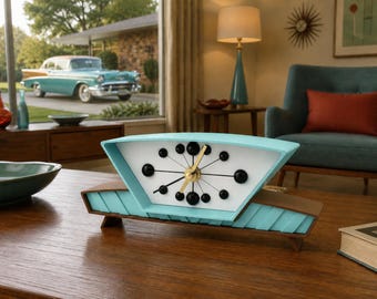 May include: A mid-century style mantle clock with a trapezoidal turquoise frame and a white face. The clock features black spherical hour markers, thin black hands, and gold-colored center hands. The base is constructed from dark brown wood.