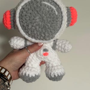 以下が含まれることがあります： 手作りの宇宙飛行士の人形。 白を基調とし、ヘルメット、足、手にグレーのアクセント。 ヘルメットには大きなグレーのバイザーがあり、イヤーカップは明るいネオンオレンジ色です。 柔らかく、抱きしめたくなるような人形です。