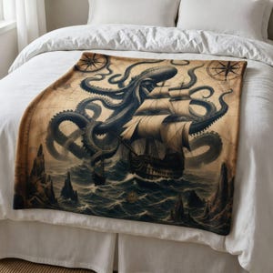 Op de afbeelding: Een rechthoekige plaid met een sepia-kleurige vintage kaartachtergrond met een grote donkere octopus die zijn tentakels om een zeilschip met meerdere masten op woelige golven slaat, omringd door rotsachtige kliffen en kompasroos-iconen.
