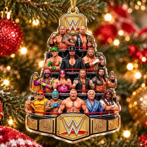 May include: A flat, tiered Christmas tree-shaped ornament featuring a collage of WWE wrestlers. The design includes the WWE logo at the top and bottom, with multiple wrestlers arranged in rows, finished with a gold-toned border and a hanging loop.