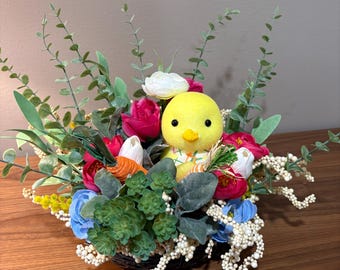 Arreglo floral de Pascua con pollito, huevos en tonos pastel y decoración rústica para mesa.