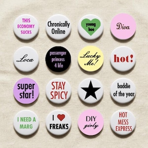May include: A collection of sixteen round pinback buttons with various phrases and graphics. The buttons feature text like "This Economy Sucks," "Super Star!," and "Hot Mess Express." Colors include white, pink, black, and yellow.