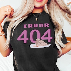 May include: Black t-shirt with the text "ERROR 404" in pink, featuring a cartoon dove illustration. The shirt is a casual style.