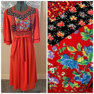 May include: A red vintage dress with a patchwork bodice featuring floral patterns in red, black, and blue. The dress has a tie belt and long sleeves with velvet trim.