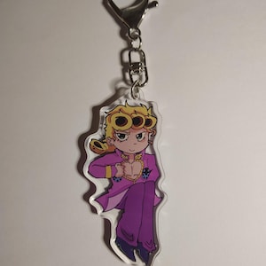 Puede incluir: Un llavero de acrílico transparente con un personaje de dibujos animados de cabello rubio peinado en tres rizos circulares, que viste una chaqueta morada con un corte en forma de corazón en el pecho y pantalones morados a juego con un cierre de metal.