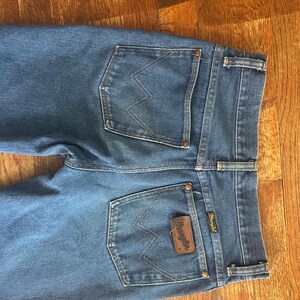 Puede incluir: Vaqueros azules de mezclilla con el logo de Wrangler en el bolsillo trasero. Los vaqueros tienen un estilo cl&aacute;sico de cinco bolsillos con corte recto. Los bolsillos traseros presentan las costuras distintivas de Wrangler.
